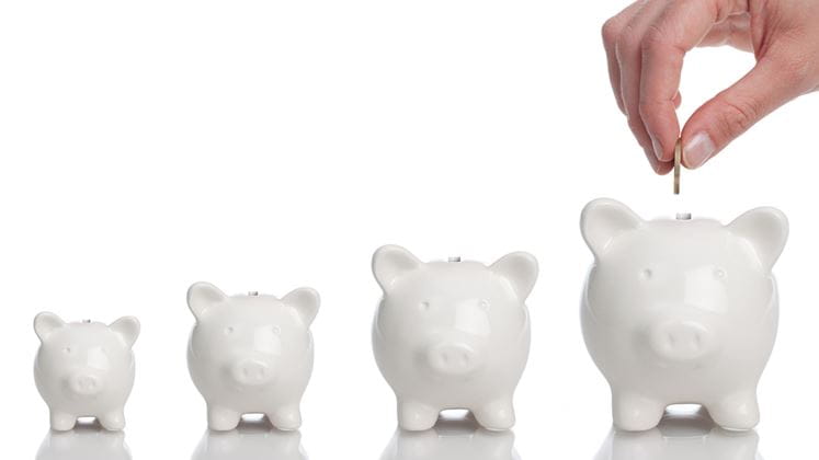 Hand inserting money into piggy banks