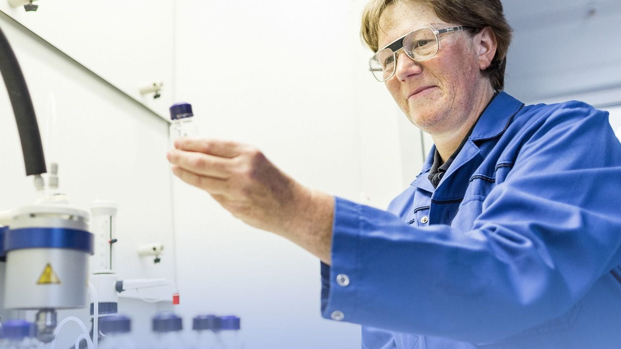 Laboratory technician observing container with sample in her hand