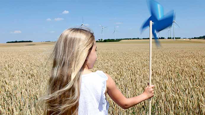 Criança com um moinho de vento na mão num campo de trigo